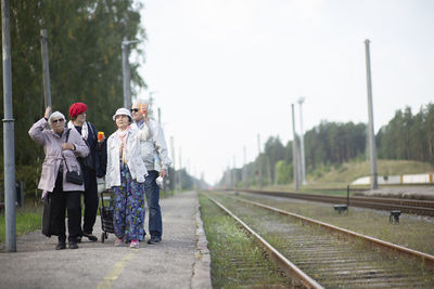 Group of positive elderly seniors old people waiting train before traveling during a pandemic