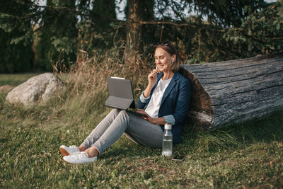 Woman working on laptop in park. distant remote job. video blogger doing live stream.