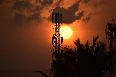 Silhouette communications tower against sky during sunset