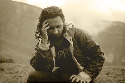 Side view of young man sitting on field