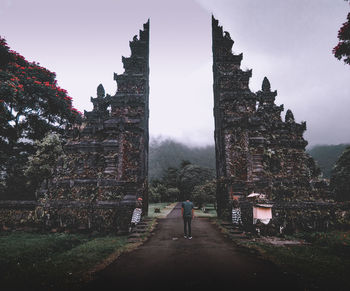 Rear view of people walking outside temple against sky