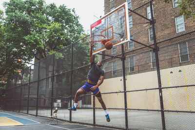 Young man scoring goal at basketball court