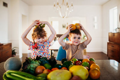 Young boy and girl sitting at kitchen counter playing with fruit