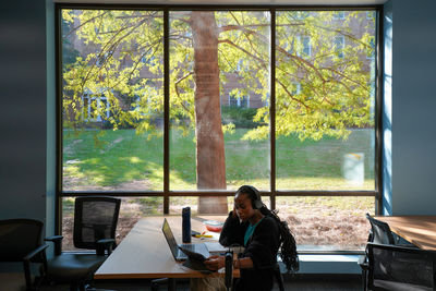 Rear view of woman sitting on window