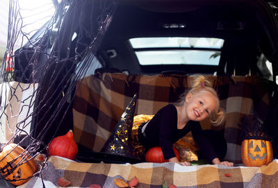 Portrait of cute girl sitting by halloween equipment