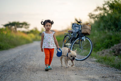 Portrait of cute girl with dog on dirt road