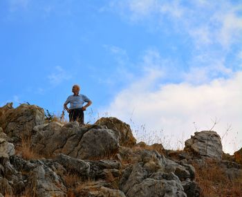 Low angle view of senior man standing with hands on hip at hill