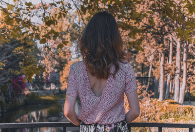 Rear view of woman standing against trees during autumn