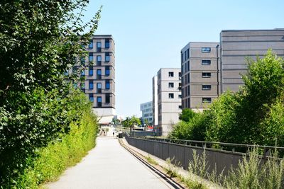 Footpath amidst buildings in city against clear sky