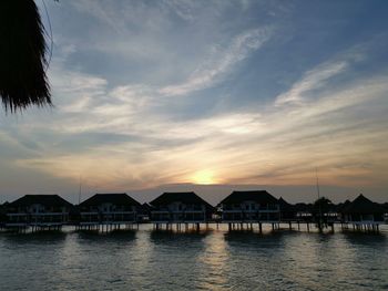 Houses by sea against sky during sunset