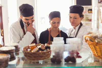 Male and female owners looking at display cabinet in grocery store