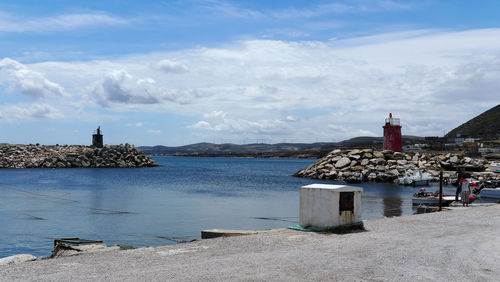 Lighthouse by sea against buildings