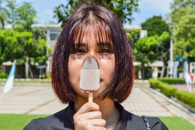 Portrait of teenage girl holding ice cream outdoors
