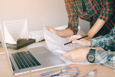 Architects discussing over blueprint at desk in office