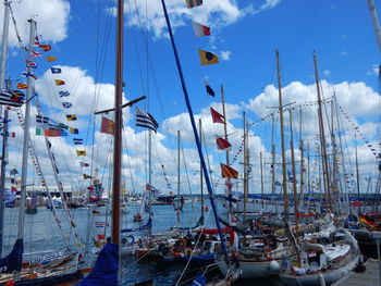 Sailboats moored on harbor against sky