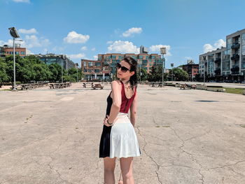 Portrait of young woman wearing sunglasses standing against built structure