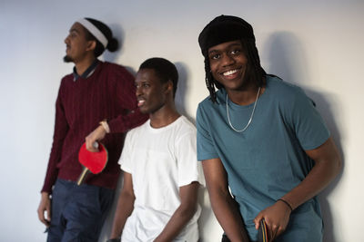 Smiling teenage boy with friends against wall in games room