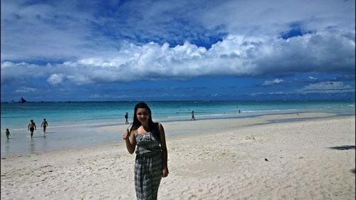 Portrait of smiling woman standing at beach against sky