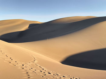 Distant view of man walking on desert against sky