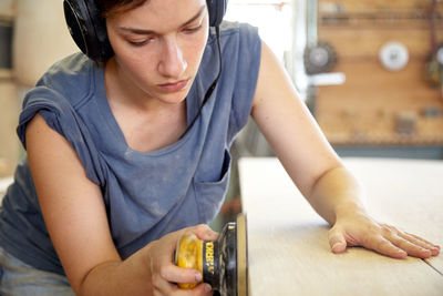 Carpenter sanding wooden plank in carpentry workshop