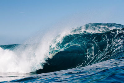 Waves splashing in sea against clear sky