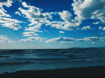 Scenic view of beach against cloudy sky