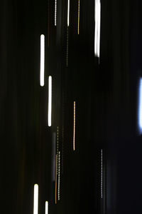 Close-up of illuminated lamp hanging against black background