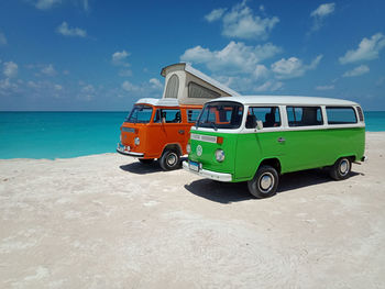 Vintage car on beach against blue sky