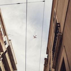 Low angle view of buildings and power lines against sky