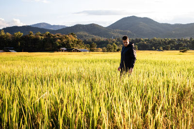 Side view of man standing at rice paddy against mountains