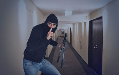 Portrait of burglar holding work tool standing in corridor