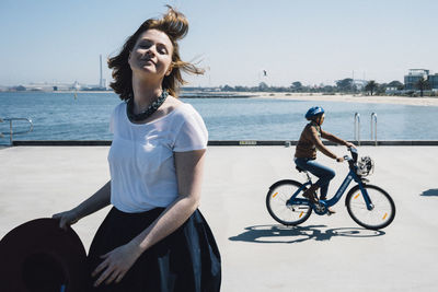 Young woman riding bicycle on beach against clear sky