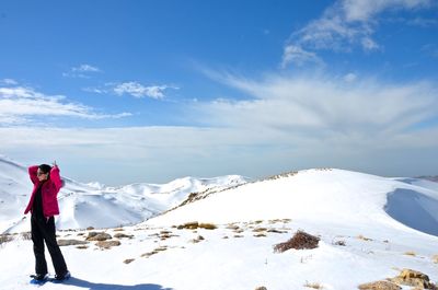 Full length of woman standing on snowcapped mountains against cloudy sky