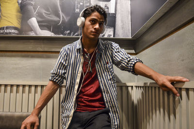 Portrait of young man standing against railing