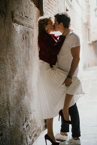 Side view of young couple kissing against wall