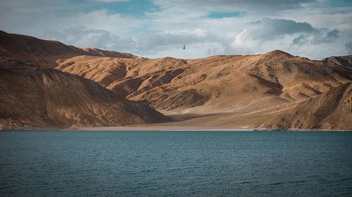 Scenic view of sea and mountains against sky