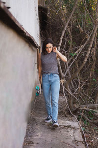 Full length of woman with skateboard walking by building