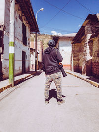 Rear view of man walking on street against building