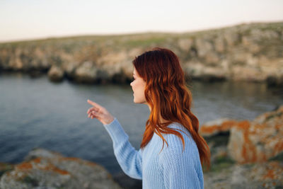 Side view of young woman standing on rock