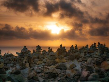 Stack of rocks on beach against sky during sunset