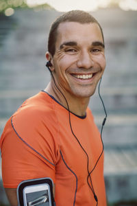 Portrait of smiling man wearing headphones at park