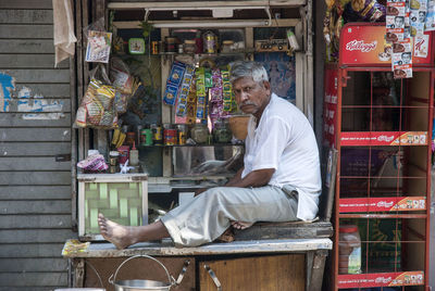 Side view of a man sitting on table at store