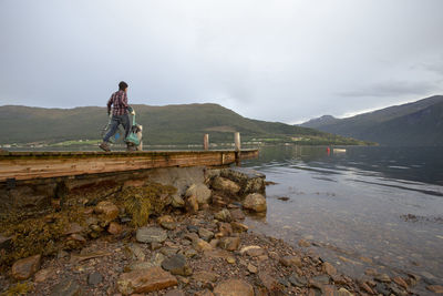 A man carrying some crab pots along a dock in norway