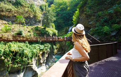 Woman walking on the path into the wild enjoying landscape with waterfalls and a natural canyon