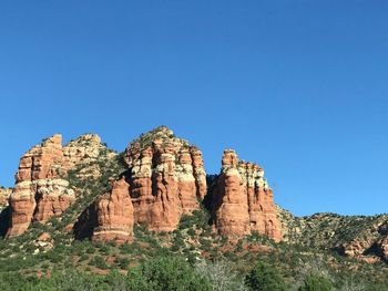 Low angle view of rock formation against clear blue sky