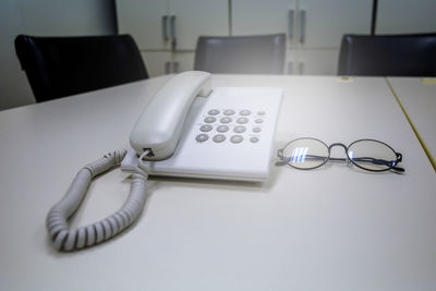 High angle view of telephone and eyeglasses on table
