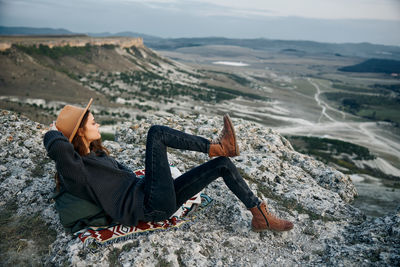 Rear view of woman sitting on rock