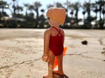 Boy sculpture on sand at beach against sky