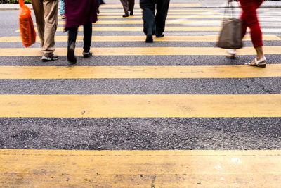 Low section of people walking on zebra crossing