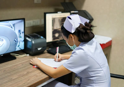 Nurse writing in paper at table in hospital